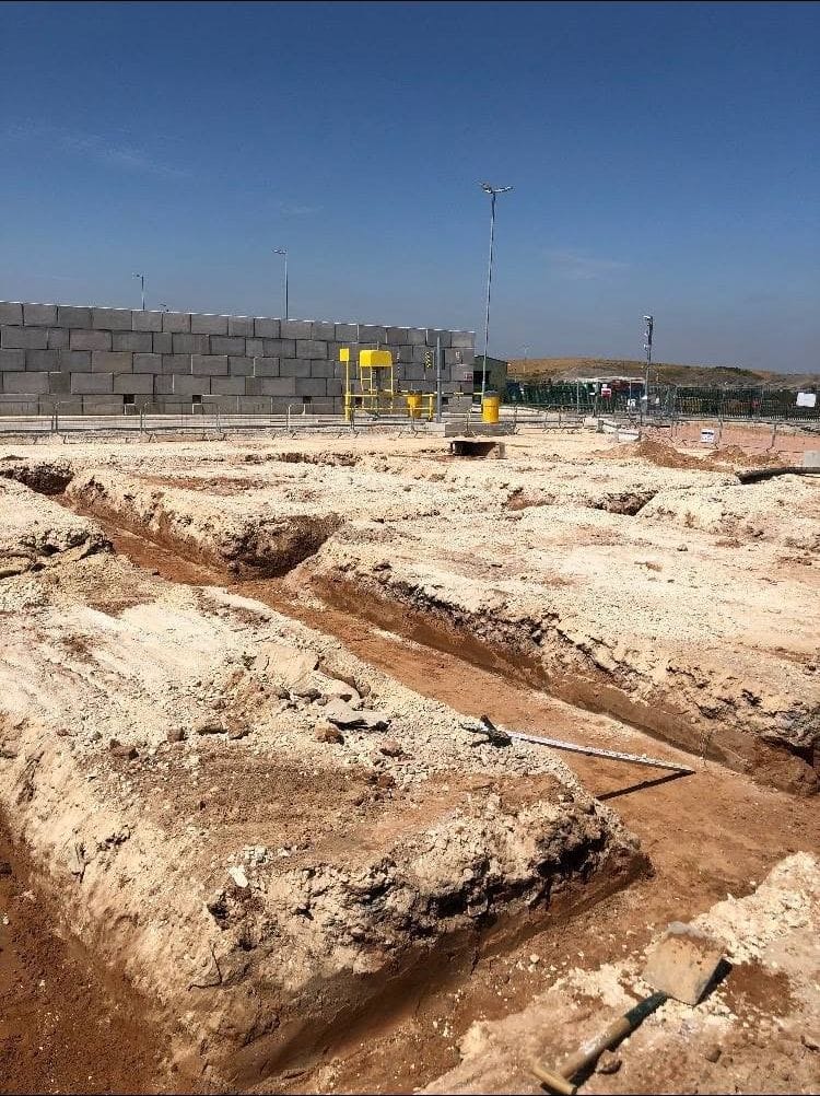 Excavated foundation trenches on a construction site under a clear blue sky